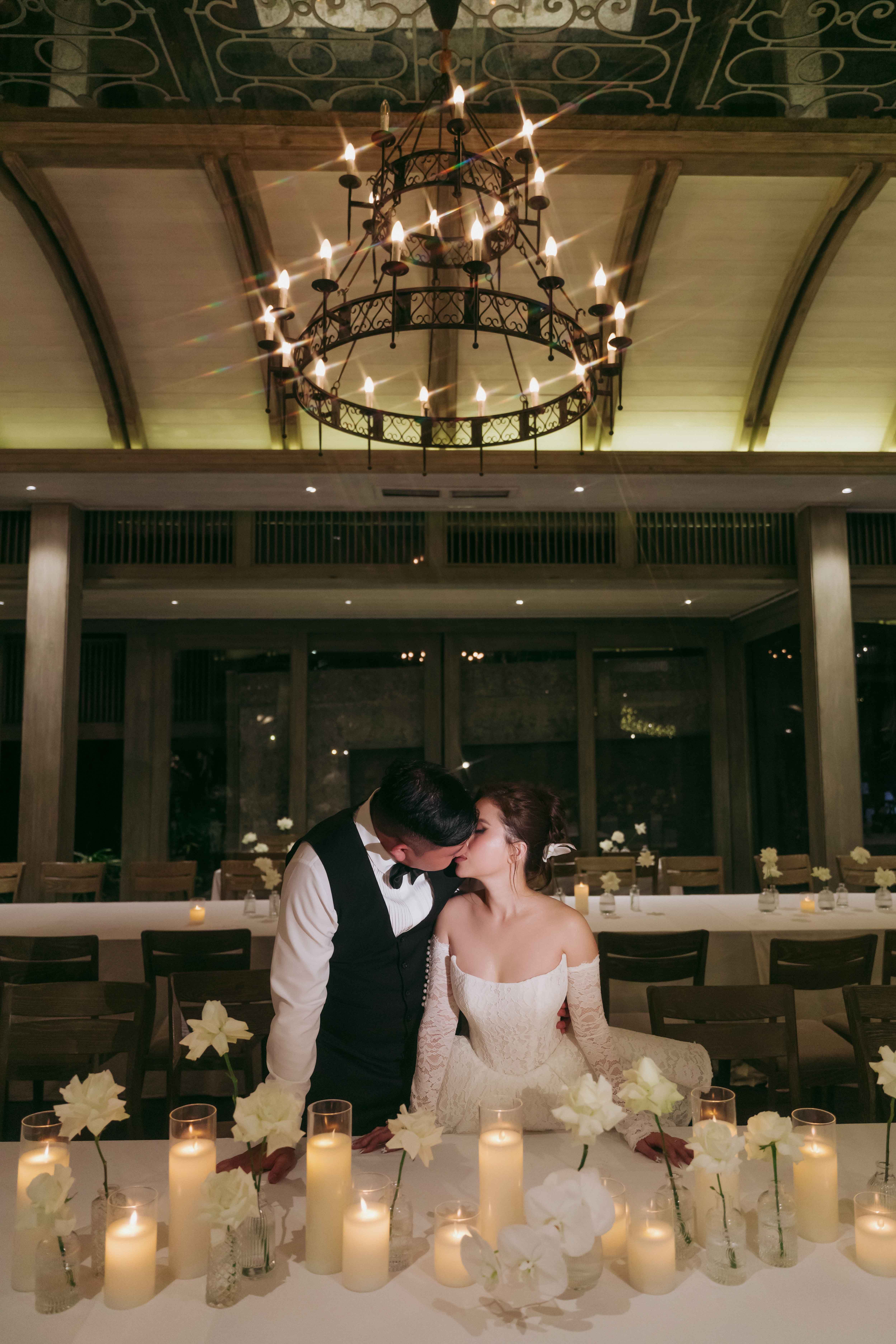 Hương và Đức hôn nhau tại bàn tiệc chính sau hàng nến và hoa trắng